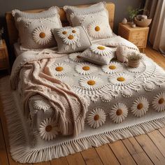 a bed with white and yellow flowers on the comforter, pillows and throw blanket