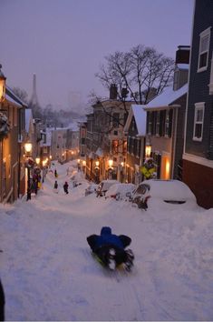 a sled pulled up the side of a snow covered hill in front of houses