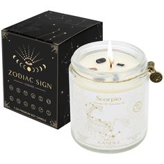 a candle in a glass jar next to a black box with the zodiac sign on it