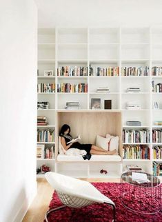 a woman laying on a couch in front of a bookshelf filled with books