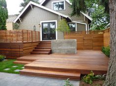 a wooden deck in front of a house with steps leading up to the patio area