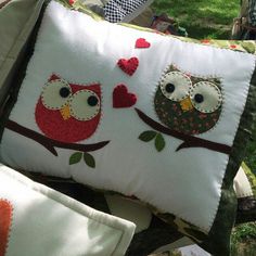 two owls sitting on top of pillows in the grass