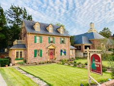 a brick house with green shutters and a red sign in front of it that says the cedardale club