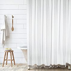 a bathroom with white walls and wooden flooring, a bathtub and shower curtain