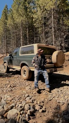 a man sitting on the ground next to a truck with a large piece of wood in it's bed