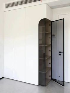 an empty room with white cupboards and black shelves on the wall next to each other