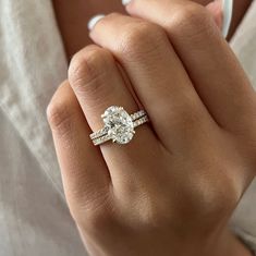 This exquisite engagement ring set showcases a brilliant 3-carat oval lab-grown diamond, complemented by the shimmering beauty of pave-set diamonds. The oval diamond radiates exceptional quality with its brilliant cut facets, while the hidden halo design frames it with smaller accent diamonds, creating a mesmerizing effect. The band itself is adorned with french pave diamonds, adding a sparkling brilliance that enhances the ring's overall allure. Each diamond is securely set in a shared prong se Two Wedding Bands With Engagement Ring Bridal Sets, Oval Diamond Ring With Diamond Band, Oval Shaped Engagement Rings White Gold, Oval Diamond Band Engagement Ring, French Pave Oval Engagement Ring, Rose Gold Wedding Ring Oval, Oval Engagement Ring With Accent Band, Raised Oval Engagement Ring, Wedding Ring Set Oval Diamond