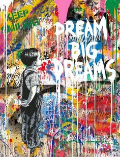 a boy standing in front of a graffiti covered wall with the words dream big dreams on it