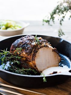 a roasting pan with meat and vegetables in it on a wooden table next to utensils