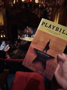 a person holding up a book about playbill