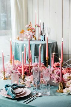 a table set with pink flowers, candles and plates for a formal dinner or bridal party