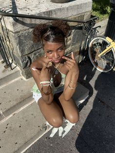 a woman sitting on the steps with her hands in her mouth and looking at the camera