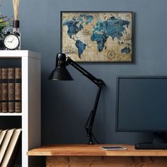 a desk with a computer, books and a clock on it in front of a blue wall