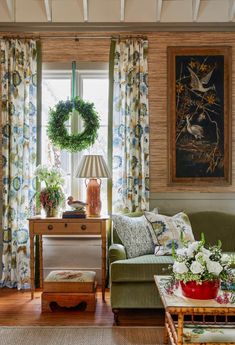 a living room filled with furniture next to a window covered in curtains and wreaths