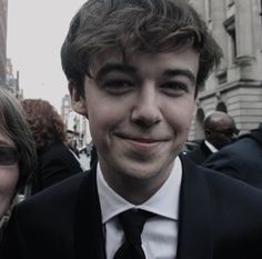 a man in a suit and tie standing next to a woman with glasses on her face