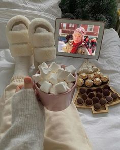 a person's feet with marshmallows in front of them on a bed