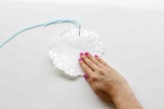 a woman's hand is holding a doily on top of a white surface