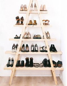 there is a ladder that has many pairs of shoes on it in front of a white wall