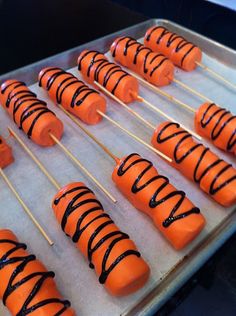 several skewered carrots with chocolate drizzled on them sitting on a baking sheet