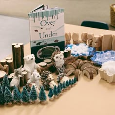 there is a book about over under on the table next to fake trees and animals