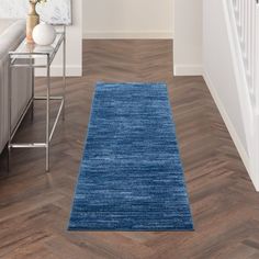 a blue runner rug in the middle of a living room with hardwood floors and white walls