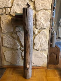 a wooden pole sitting on top of a hard wood floor next to a stone wall