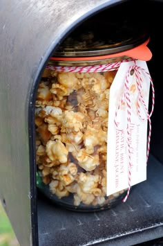 a jar filled with nuts sitting on top of a mailbox next to a red and white striped ribbon