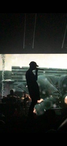 a man standing on top of a stage holding a microphone to his ear in front of a crowd