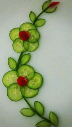 a flower made out of cucumbers and leaves on a white surface with red flowers