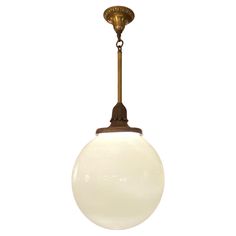 an old fashioned light fixture with a white glass ball hanging from it's side