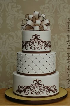 a three tiered cake with brown designs on it