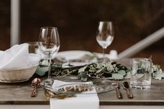 the table is set with glasses, plates and napkins