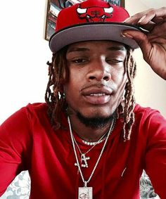 a man with dreadlocks wearing a red shirt and a chicago bulls baseball cap