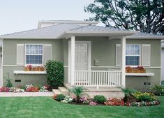 a house that has flowers in the front yard and landscaping on the lawn around it