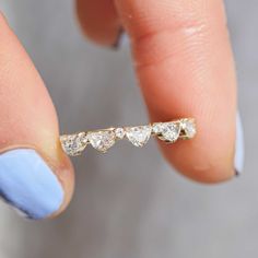 a woman's hand holding a gold ring with five small diamonds on the side