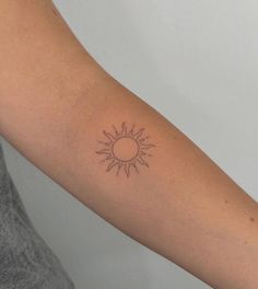 a woman's arm with a small sun tattoo on the left side of her arm