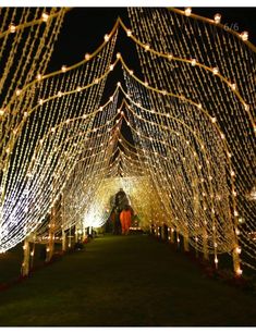 the inside of a tent covered in lights and string lights at night with people walking through it