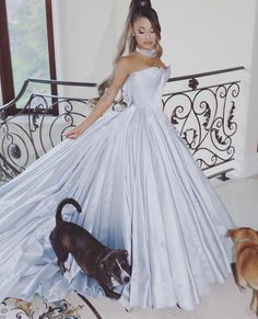 a woman in a white dress standing next to two dogs