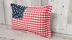 a red and white checkered pillow with an american flag patch on the front side