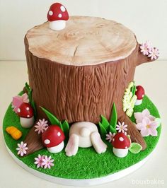 a cake made to look like a tree stump with mushrooms and flowers around it on a plate