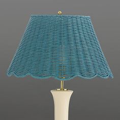 a blue lamp with a white base and gold trim on the shade is sitting against a gray background