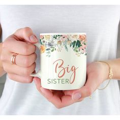 a woman holding a coffee mug that says big sister