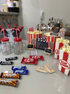 popcorn, movie tickets and candy are on the table in front of some snacks that have been placed around them