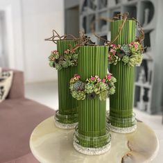 three green vases with plants in them on a table