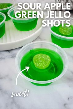 green jello shots in plastic cups on a marble counter top with text overlay reading sour apple green jello shots