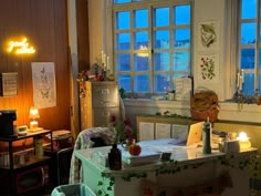 a room filled with lots of clutter and furniture in front of two large windows