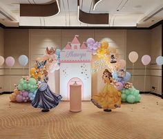 an indoor birthday party with balloons and princess figures on the floor, including a castle