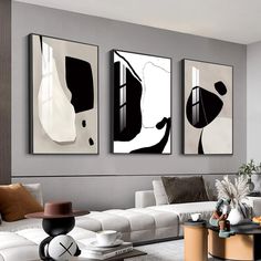 three black and white paintings hanging on the wall in a living room