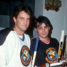 two young men sitting next to each other holding hockey sticks and wearing jerseys with stars on them