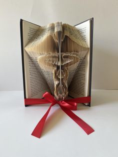 an origami folded book with red ribbon